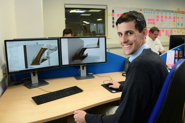 Design engineer in front of PC with stair renders on